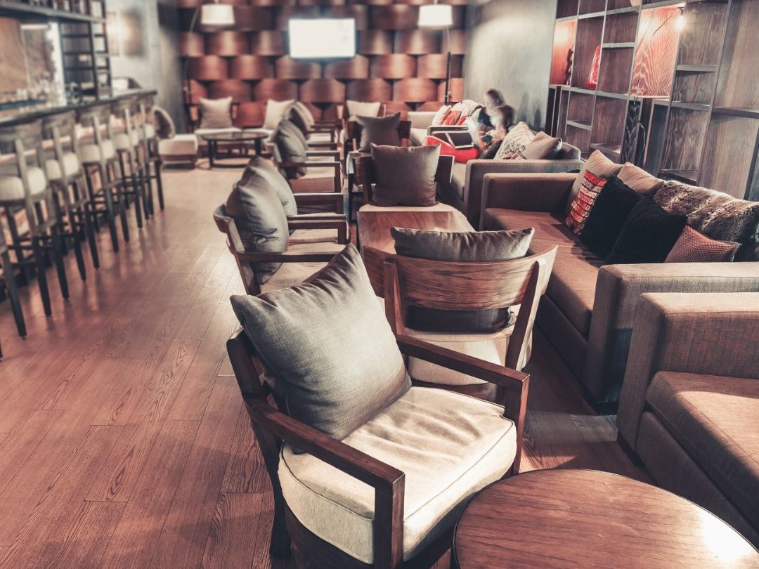 The room from the bar end, stools along the lit stone counter, armchairs and sofas set in separate groups down the other side