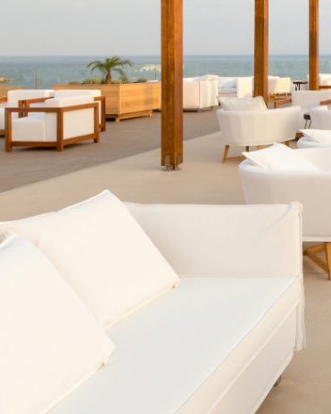 A white sofa and a timber stool on pale stone, nobody on it